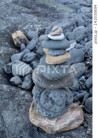 Balancing stone cairn stacked on a rocky beach, symbolizing zen, harmony and mental balance 141030694