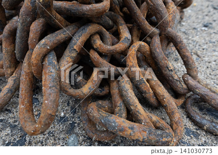 Close-up of a heavy rusty iron chain tangled in a pile on a ground Close-up of a heavy rusty iron chain tangled in a pile on a ground 141030773
