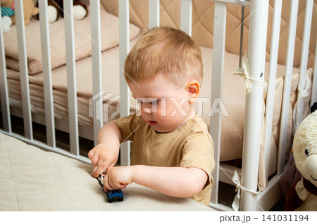 Two year old boy playing with small cars on bed. Racing and parking toy vehicles. Fine motor skills through push and go play. Classic boyish toy fun Two year old boy playing with small cars on bed. Racing and parking toy vehicles. Fine motor skills through push and go play. Classic boyish toy fun 141031194