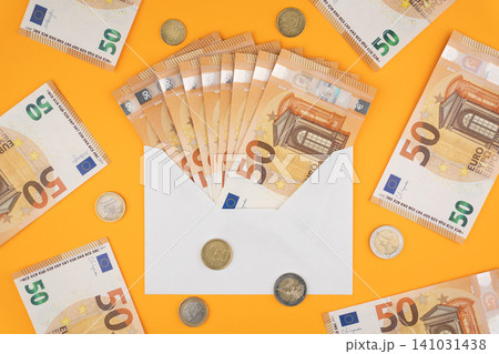 50 euro bills in an envelope and various coins on an orange background 50 euro bills in an envelope and various coins on an orange background 141031438
