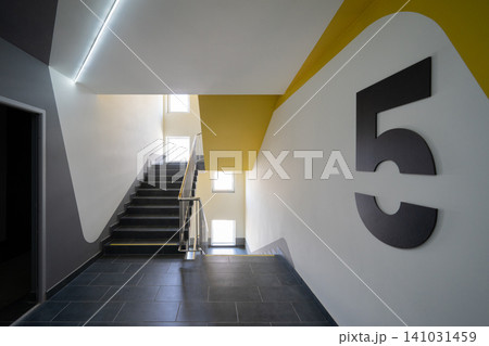 Modern apartment building staircase with bold yellow accent and floor numbering Modern apartment building staircase with bold yellow accent and floor numbering 141031459