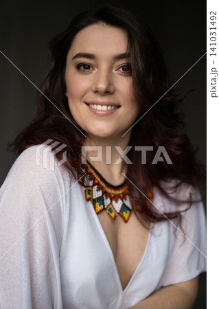 a beautiful young girl in a white dress with a handmade jewelry necklace around her neck 141031492