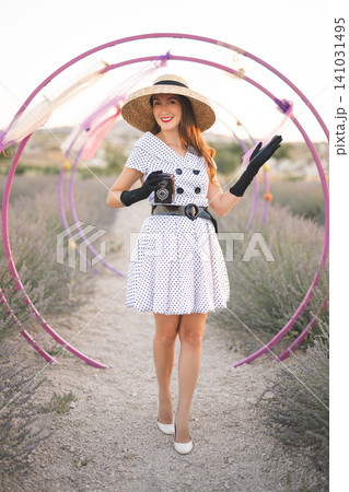 beautiful girl in retro dress and old camera posing on lavender field with scenery beautiful girl in retro dress and old camera posing on lavender field with scenery 141031495