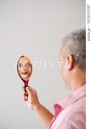 Mature Man Inspecting Smile in Hand Mirror 141031597