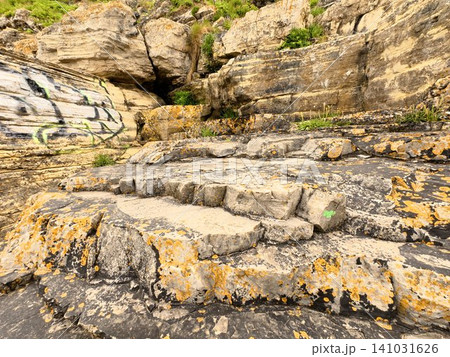Layered Coastal Rock Formation with Natural Stone Texture and Orange Lichen, Geological Background in Northern Spain Layered Coastal Rock Formation with Natural Stone Texture and Orange Lichen, Geological Background in Northern Spain 141031626