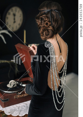 1920s style girl in backless black velvet dress with luxurious back jewelry 141031789