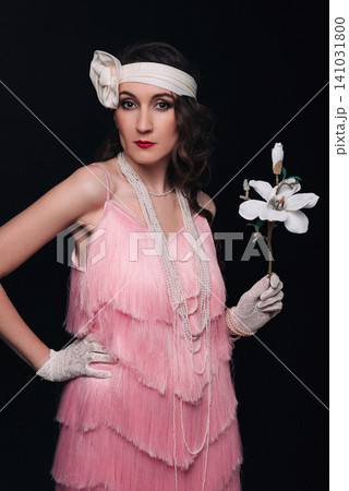 Elegant young woman and girl in 1920s style holding a white magnolia flower Elegant young woman and girl in 1920s style holding a white magnolia flower 141031800