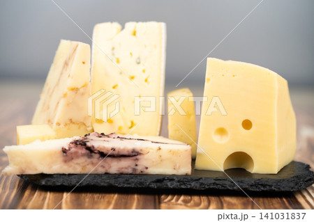 Artisanal cheese assortment on a black slate and wooden background Artisanal cheese assortment on a black slate and wooden background 141031837