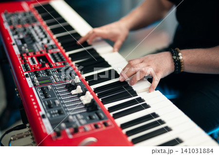 Close-up of musician's hands playing a red professional electronic keyboard synthesizer Close-up of musician's hands playing a red professional electronic keyboard synthesizer 141031884