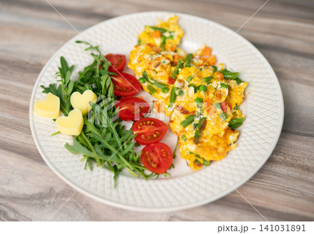 Scrambled eggs with vegetables served with arugula and cherry tomatoes Scrambled eggs with vegetables served with arugula and cherry tomatoes 141031891