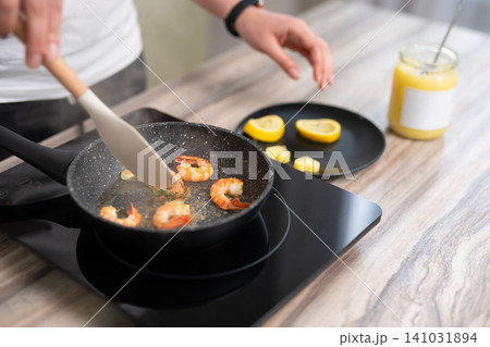 Woman pan-searing shrimp with herbs and ghee Woman pan-searing shrimp with herbs and ghee 141031894