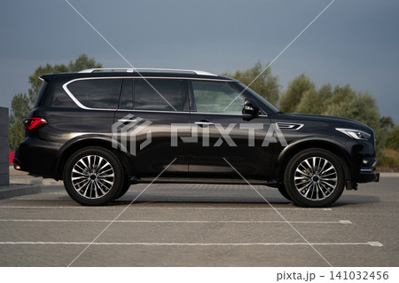 Side profile of a large black luxury SUV with tinted windows and elongated body 141032456