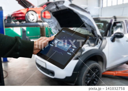 Checking the battery pack of an electric car at a service center. Checking the battery pack of an electric car at a service center. 141032758