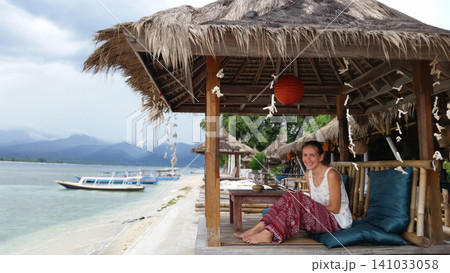 Happy woman relaxing in a beach bungalow by the ocean Happy woman relaxing in a beach bungalow by the ocean 141033058