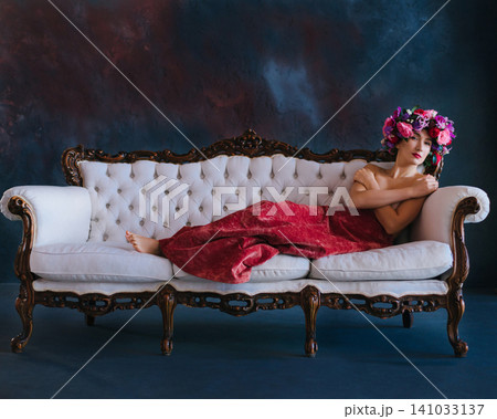 Sensual woman in flower wreath posing topless on vintage sofa Sensual woman in flower wreath posing topless on vintage sofa 141033137