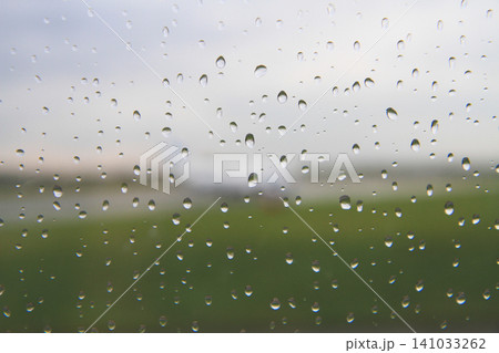 Raindrops on a window with a blurred view of an airfield 141033262