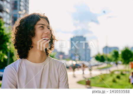 Happy teen boy with curly hair looking away outdoor Happy teen boy with curly hair looking away outdoor 141033588