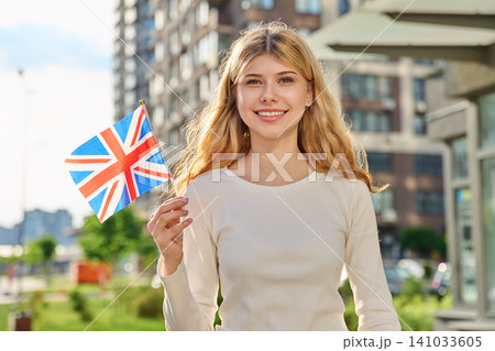 Happy girl holding British flag on sunny city street Happy girl holding British flag on sunny city street 141033605