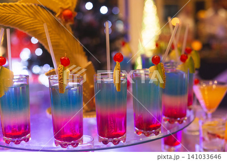 Vibrant layered cocktails with fruit garnishes at a night event Vibrant layered cocktails with fruit garnishes at a night event 141033646