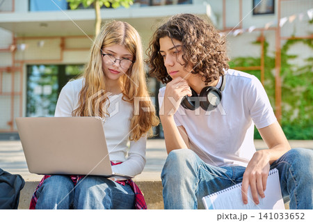 Focused teenage students studying with laptop on campus 141033652