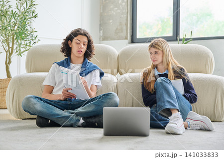 Student looking at classmate reading text book Student looking at classmate reading text book 141033833