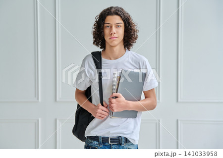 Teen student guy with laptop and backpack indoors 141033958
