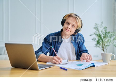 Teenage student in headphones working on his laptop Teenage student in headphones working on his laptop 141034066