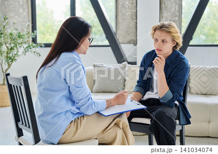 Female psychologist or counselor talking to a teenage boy patient Female psychologist or counselor talking to a teenage boy patient 141034074