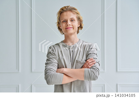 Confident teenage boy with crossed arms looking at camera against white background Confident teenage boy with crossed arms looking at camera against white background 141034105