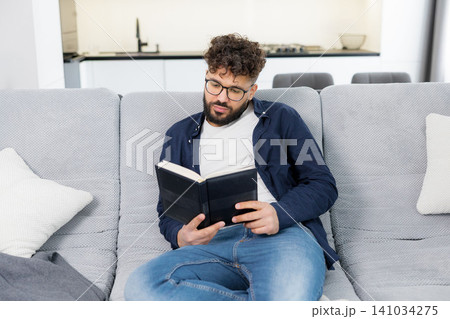 Man reading book and deeply thinking on sofa Man reading book and deeply thinking on sofa 141034275