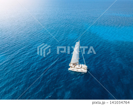 Aerial drone view of sailing catamaran yacht moving in blue sea Aerial drone view of sailing catamaran yacht moving in blue sea 141034764