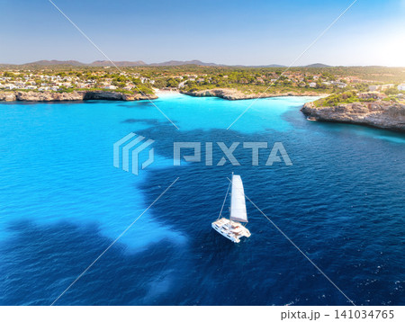 Aerial view of sailing catamaran yacht in turquoise sea water bay Aerial view of sailing catamaran yacht in turquoise sea water bay 141034765