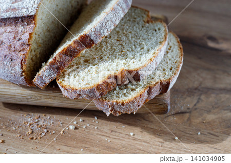 Freshly baked bread with a golden crust on a cutting board. Crispy slices of whole grain bread for bruschetta. Freshly baked bread with a golden crust on a cutting board. Crispy slices of whole grain bread for bruschetta. 141034905