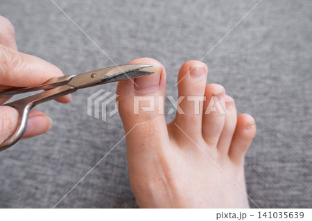 Hand Cutting Toenails with Manicure scissors Close Up Hand Cutting Toenails with Manicure scissors Close Up 141035639
