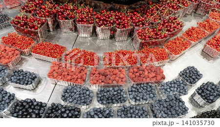 Fresh assortment of cherries, raspberries, blueberries and red currants displayed in plastic containers at a local farmers market with vibrant summer colors. Fresh assortment of cherries, raspberries, blueberries and red currants displayed in plastic containers at a local farmers market with vibrant summer colors. 141035730