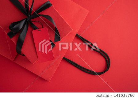 Red gift box with black ribbon and blank tag on shopping bag Red gift box with black ribbon and blank tag on shopping bag 141035760