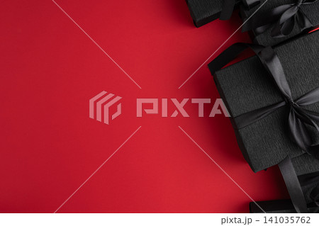 Black gift boxes with bow on red background Black gift boxes with bow on red background 141035762