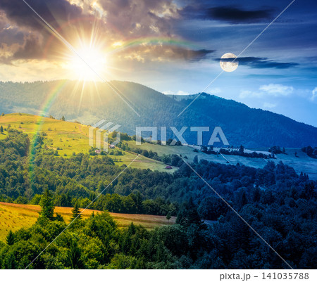 agricultural field on hillside in mountains near village. day meet night. summer solstice. sun and moon in harmony over green carpathian mountain landscape. narrow view. remote alpine farmland scene agricultural field on hillside in mountains near village. day meet night. summer solstice. sun and moon in harmony over green carpathian mountain landscape. narrow view. remote alpine farmland scene 141035788