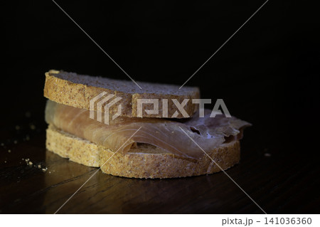 Prosciutto sandwich on dark background Prosciutto sandwich on dark background 141036360