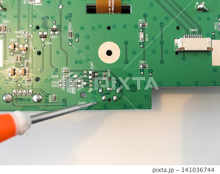 Green circuit board of a car radio being worked on with a screwdriver tool. Green circuit board of a car radio being worked on with a screwdriver tool. 141036744