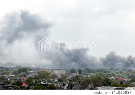 Thick black smoke rising over residential area after explosion or missile strike in Ukraine. Urban skyline under attack, air raid damage, war conflict or fire emergency concept Thick black smoke rising over residential area after explosion or missile strike in Ukraine. Urban skyline under attack, air raid damage, war conflict or fire emergency concept 141036857