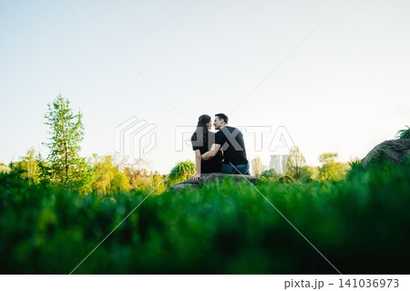 Couple enjoys a romantic moment amidst lush greenery in the park Couple enjoys a romantic moment amidst lush greenery in the park 141036973