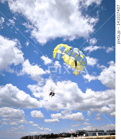 Two people are parasailing behind a boat in a cloudy sky. 141037407