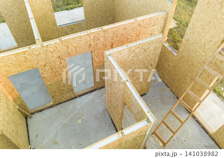 Construction of new and modern modular house. Walls made from composite wooden sip panels with styrofoam insulation inside. Building new frame of energy efficient home concept. Construction of new and modern modular house. Walls made from composite wooden sip panels with styrofoam insulation inside. Building new frame of energy efficient home concept. 141038982