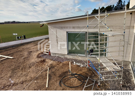 Facade of building made from white blocks with big windows under construction works. Facade of building made from white blocks with big windows under construction works. 141038993