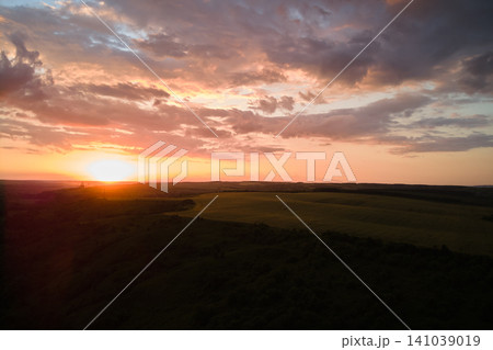 Aerial landscape view of yellow cultivated agricultural field with ripe wheat on vibrant summer evening Aerial landscape view of yellow cultivated agricultural field with ripe wheat on vibrant summer evening 141039019