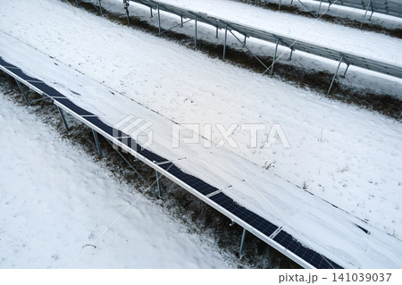 Aerial view of sustainable electrical power plant with solar photovoltaic panels covered with snow in winter for producing clean energy. Concept of low effectivity of renewable electricity in north Aerial view of sustainable electrical power plant with solar photovoltaic panels covered with snow in winter for producing clean energy. Concept of low effectivity of renewable electricity in north 141039037