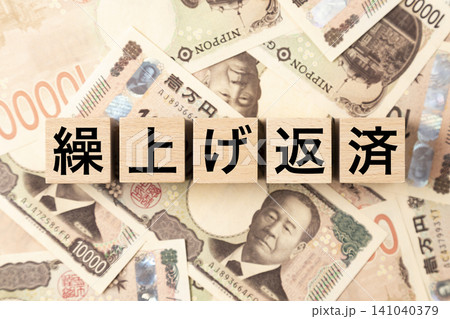 「繰上げ返済」と書かれたブロックとたくさんの一万円札 「繰上げ返済」と書かれたブロックとたくさんの一万円札 141040379