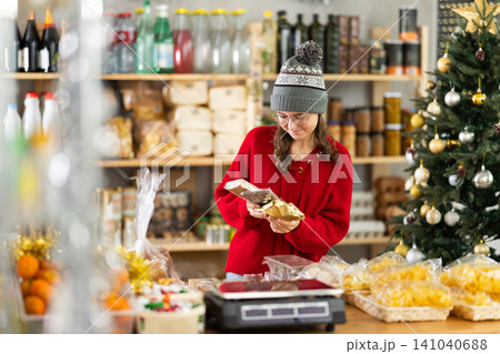 Teenage girl choosing and buying different candies and sweets for Christmas celebration Teenage girl choosing and buying different candies and sweets for Christmas celebration 141040688