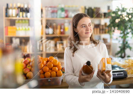 Teen girl hold packages bottles and choose consider juice in store Teen girl hold packages bottles and choose consider juice in store 141040690